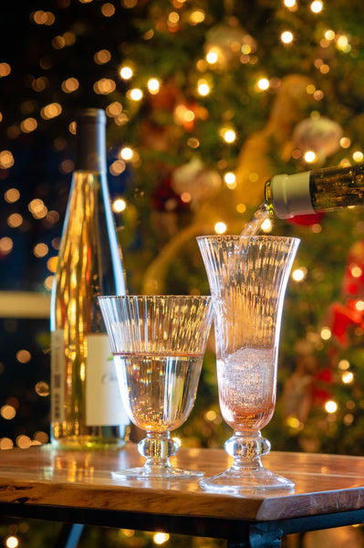 Warm pink aria champagne flute on a table in front of a Christmas tree