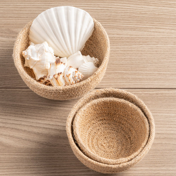 Natural woven mini bowls on a table with sea shells.