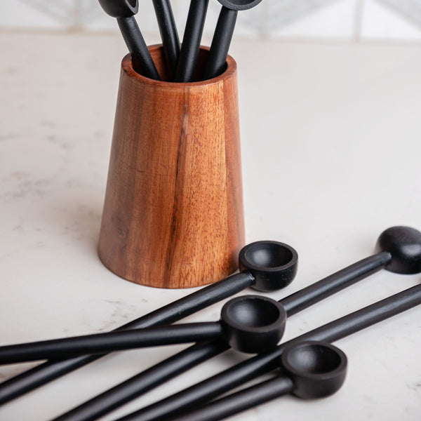 Black wood spoon sets in a vase and on a counter