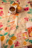 Sweet tea tasty tips tea towel unfolded with a mug of tea on top. 