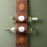 Leather hanging wine holder with two wine bottles in front of a green wall