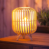 Wicker braided lantern on a table with a candle in it.