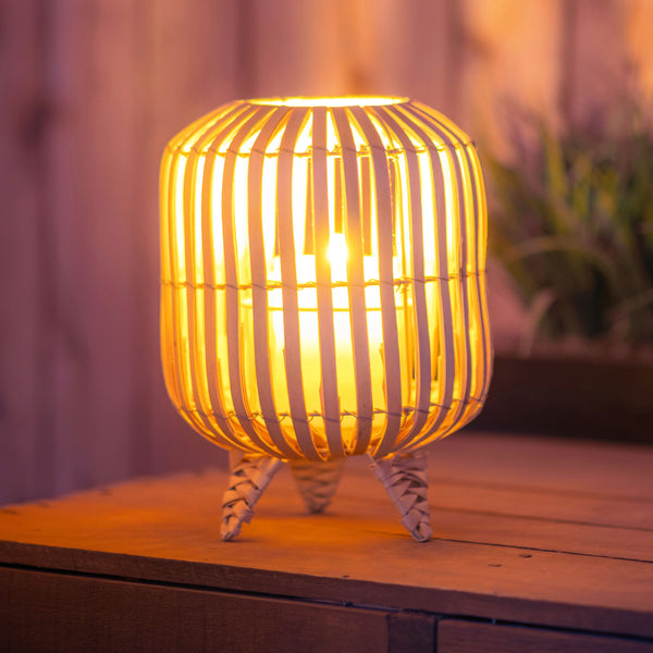 Wicker braided lantern on a table with a candle in it.
